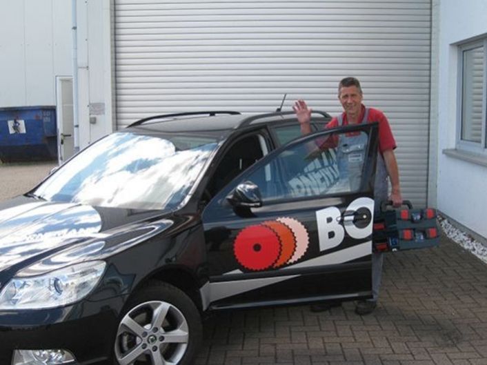 Worker holding a toolbox and entering company car